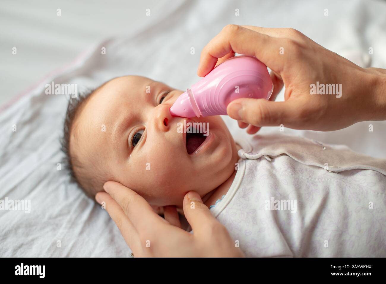 mother using baby nasal aspirator mucus nose suction Stock Photo