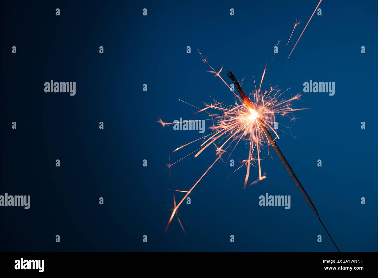 Burning sparkler bengal fire on blue background Stock Photo