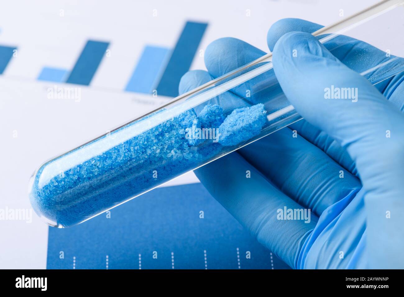 Scientist hold glass test tube with blue crystals in lab Stock Photo