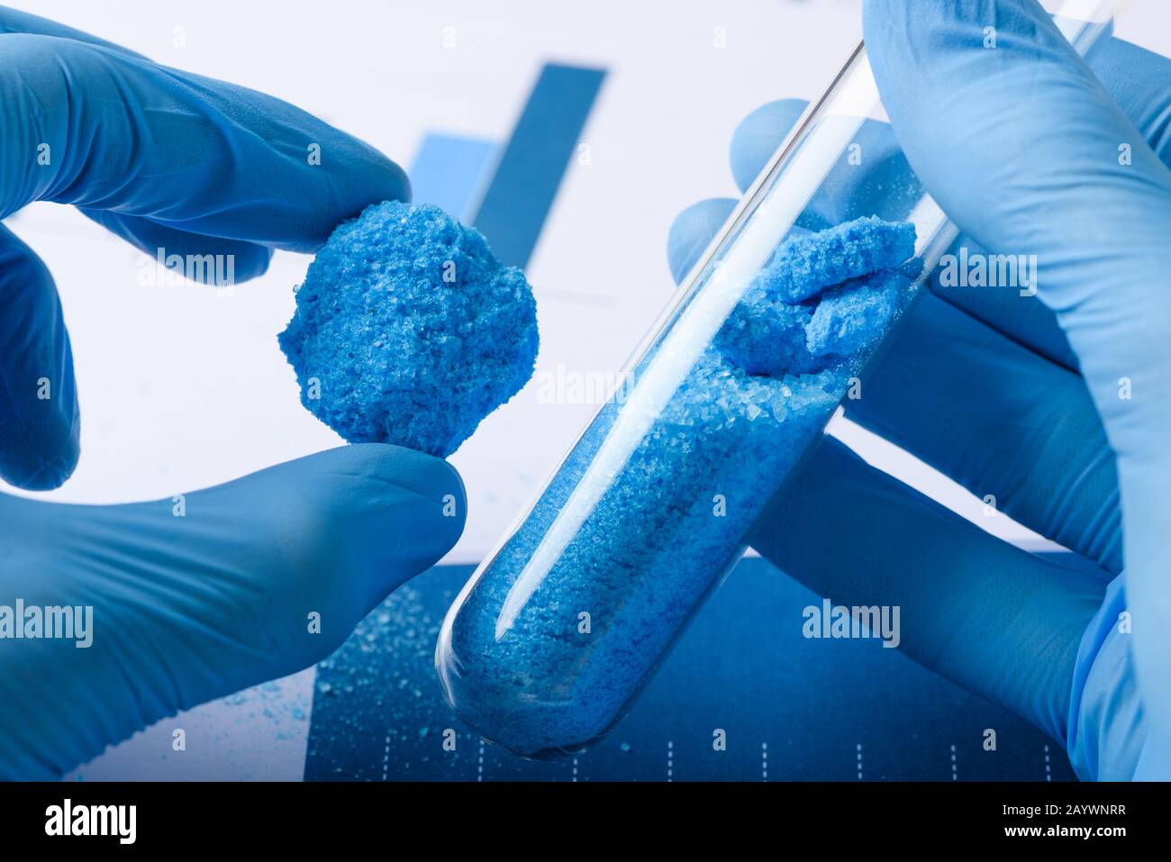 Researcher show blue crystal material in hand and glass test tube in laboratory Stock Photo