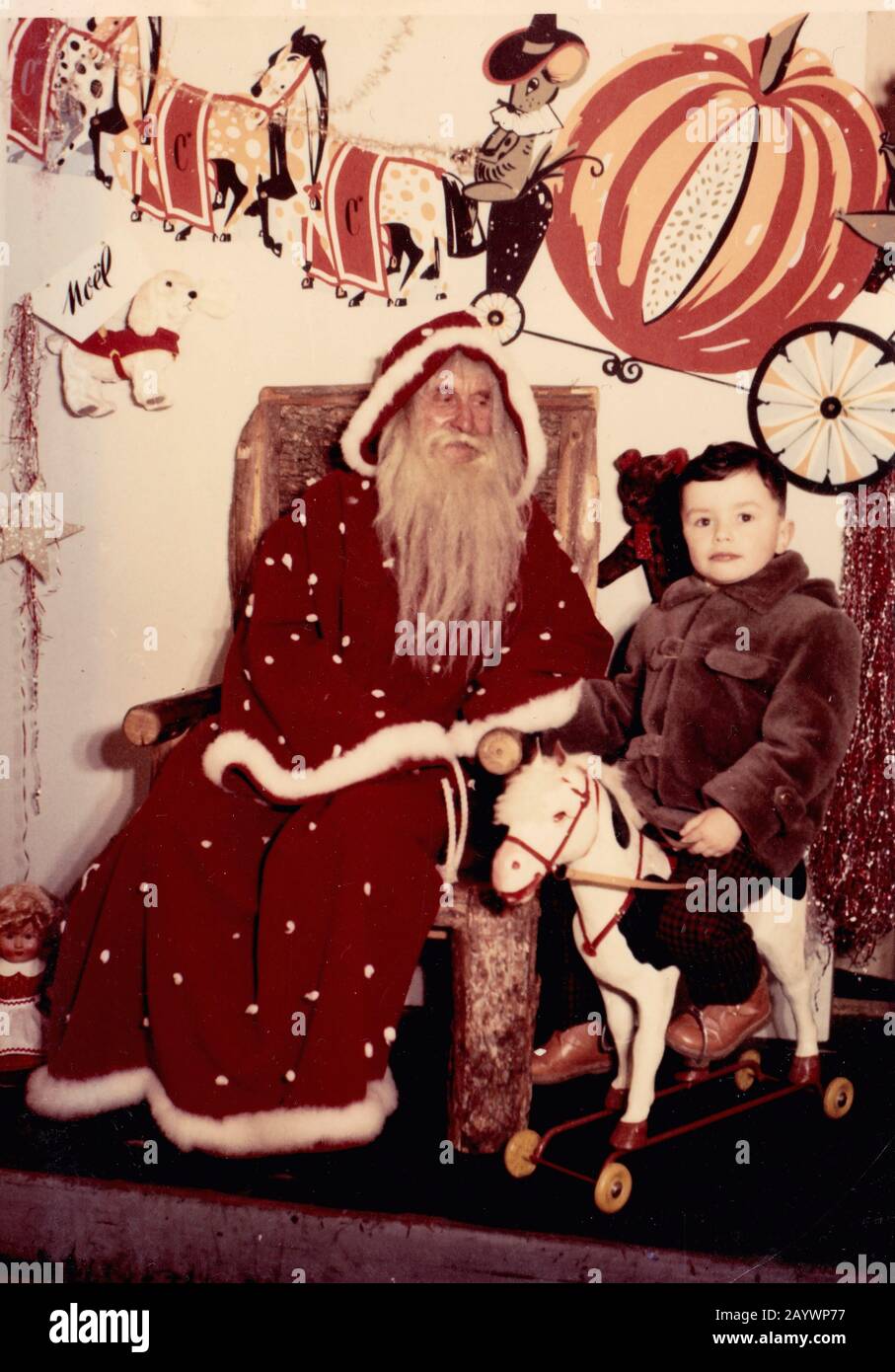 Photograph of a small boy riding a rocking horse next to Santa Claus ...