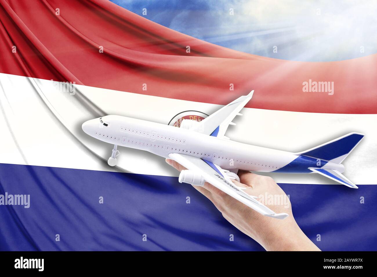 Airplane in hand with national flag of Paraguay on a background of blue sky with sunbeams Stock Photo