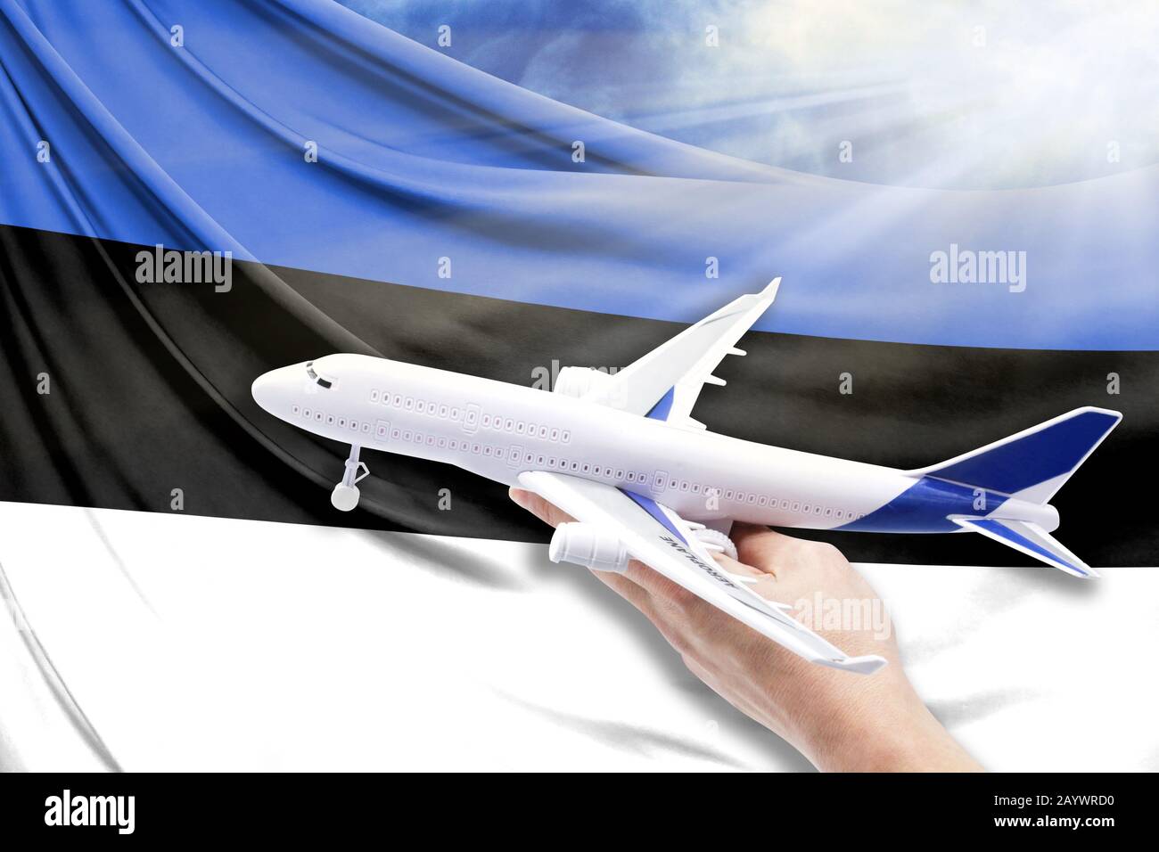 Airplane in hand with national flag of Estonia on a background of blue ...