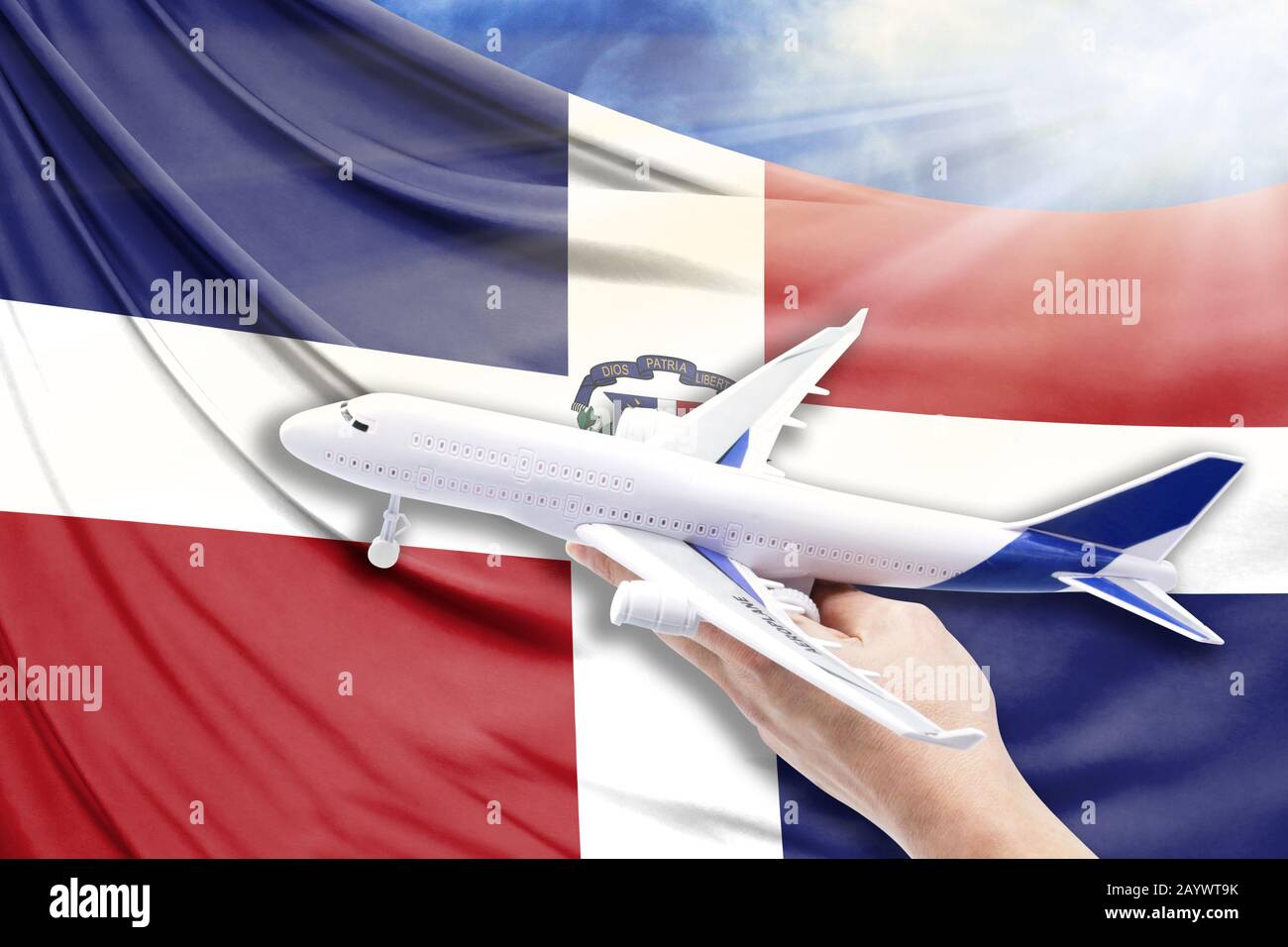 Airplane in hand with national flag of Dominican Republic on a background of blue sky with sunbeams Stock Photo