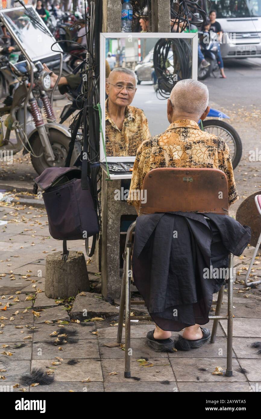 Vietnam Hanoi barber - An outdoor barber waiting for cusomers on the street of Hanoi, Vietnam, Southeast Asia. Stock Photo