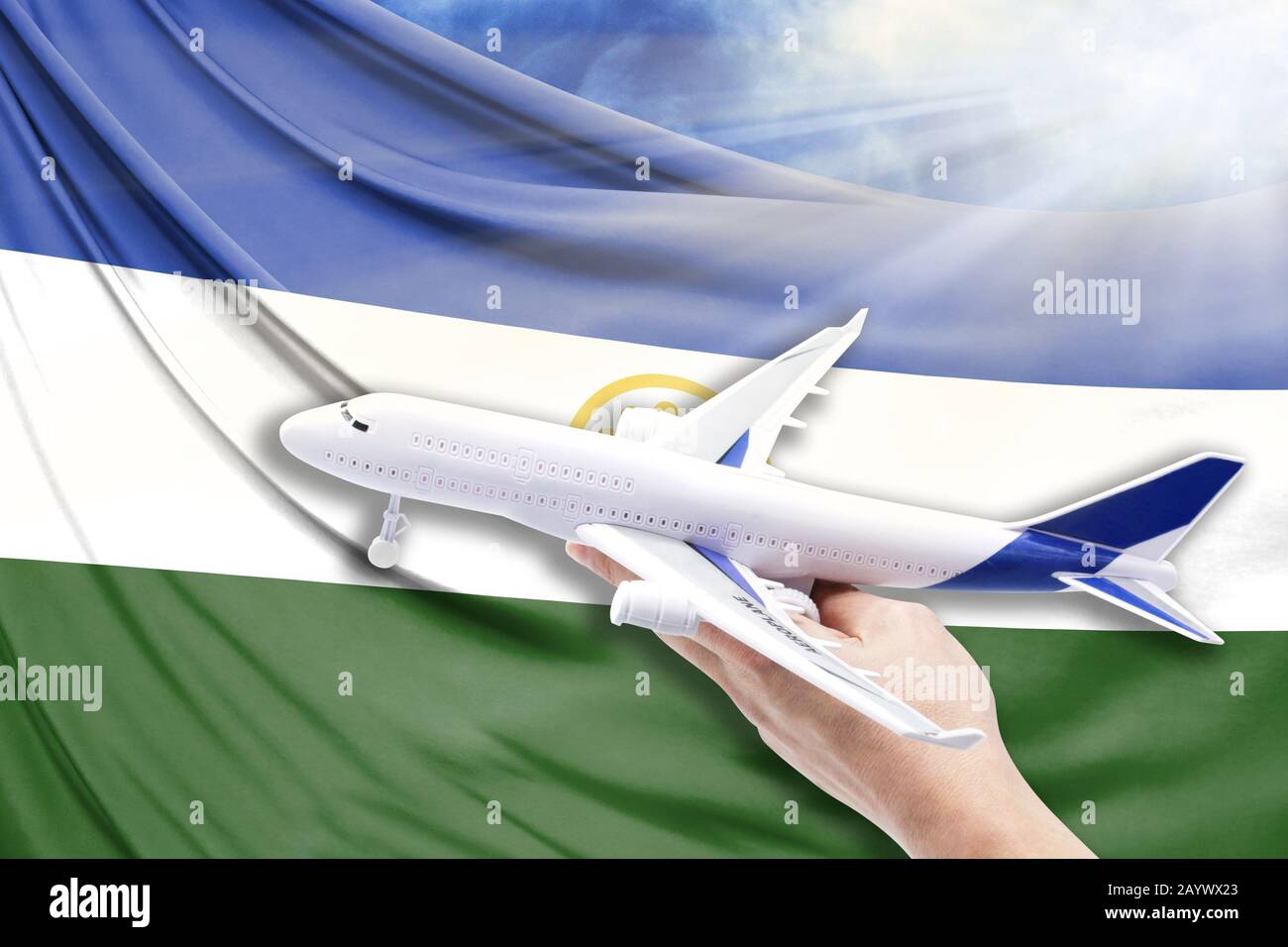 Airplane in hand with national flag of Bashkortostan on a background of blue sky with sunbeams Stock Photo