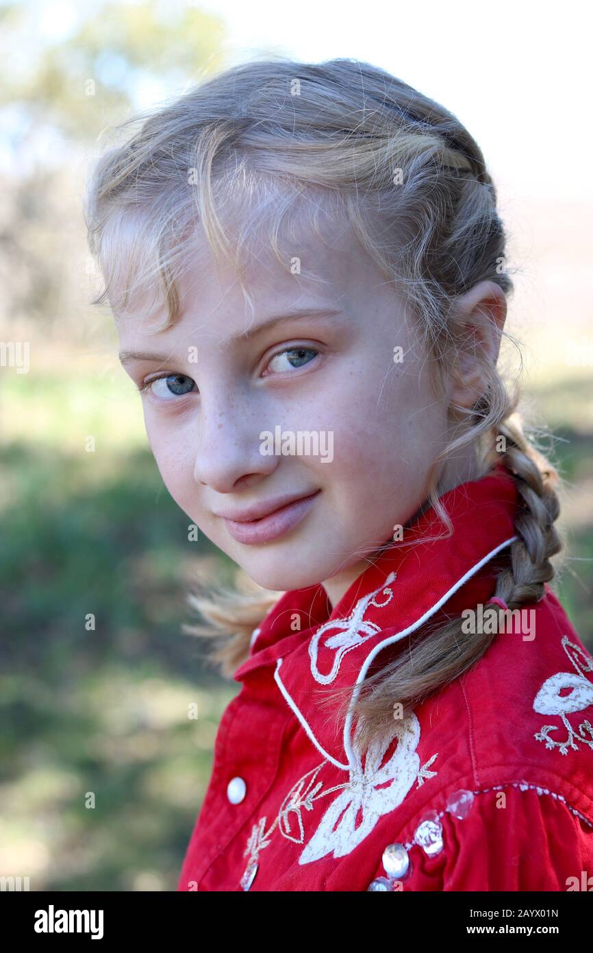 Portrait of a girl with blonde french braids wearing an elaborate cowboy shirt Stock Photo