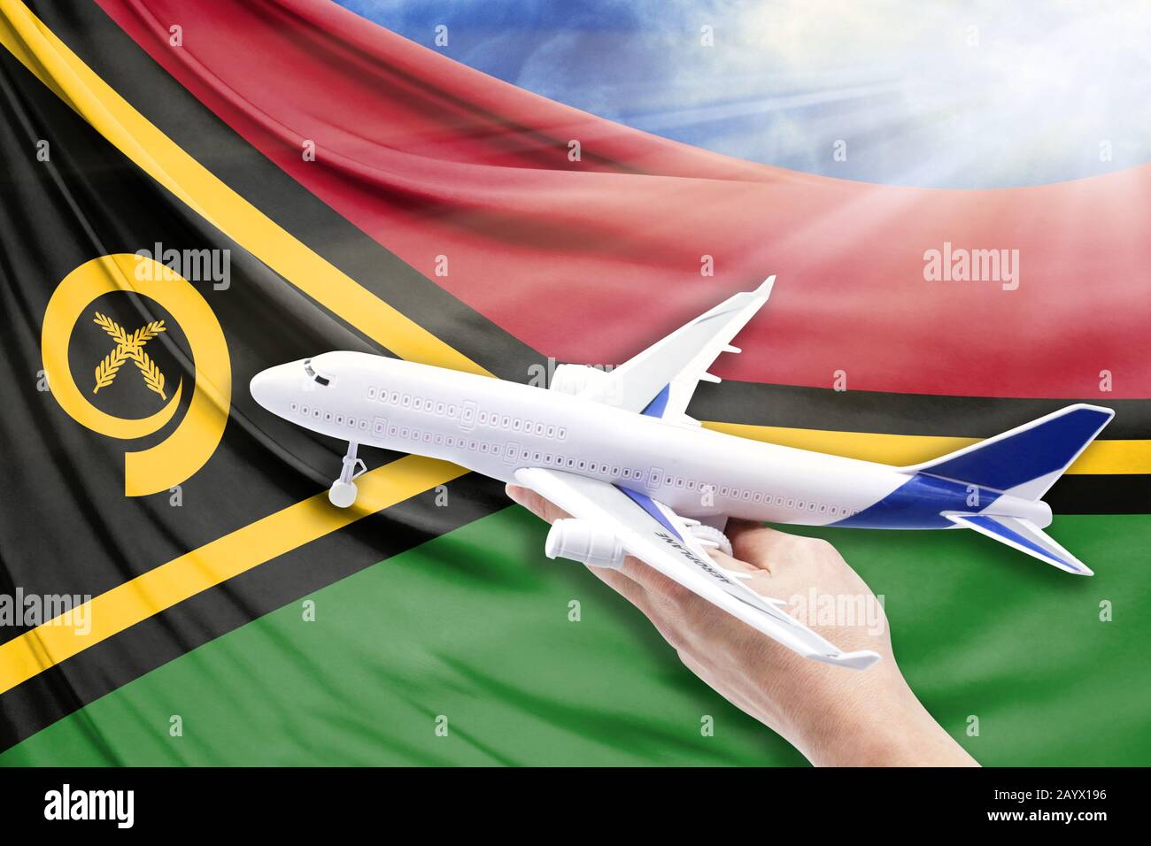 Airplane in hand with national flag of Vanuatu on a background of blue sky with sunbeams Stock Photo