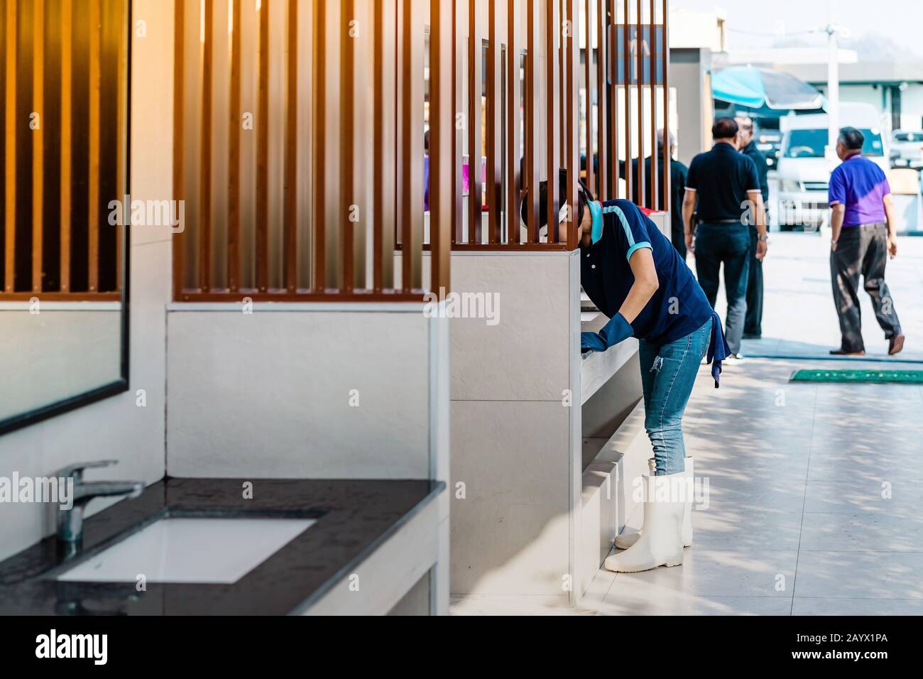 Female janitor using fabric and a detergent cleaning sink and tap in