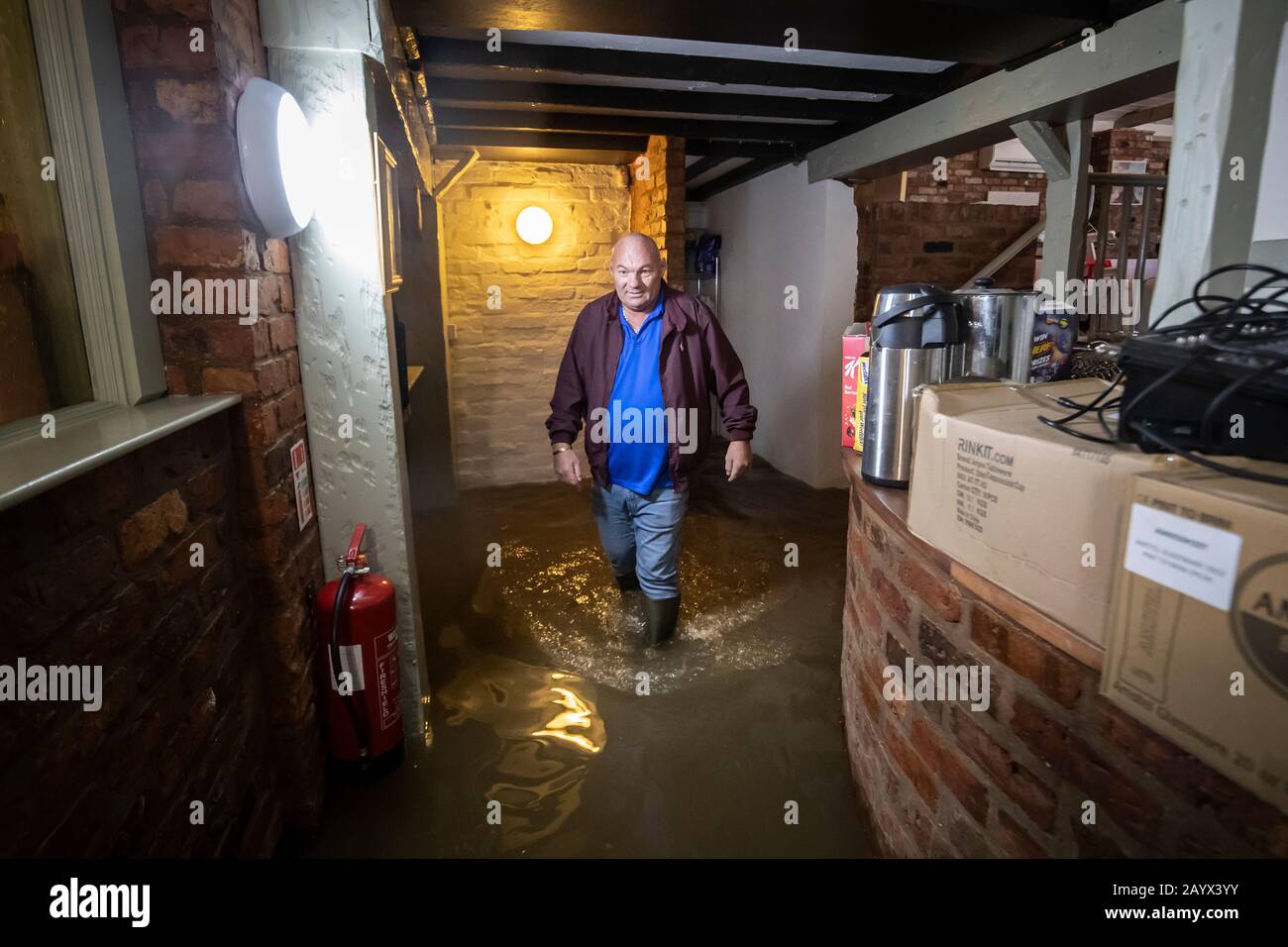 Landlord Colin Reynolds walks through flood water in the Ship Inn in Acaster Malbis, near York, in the aftermath of Storm Dennis. Stock Photo