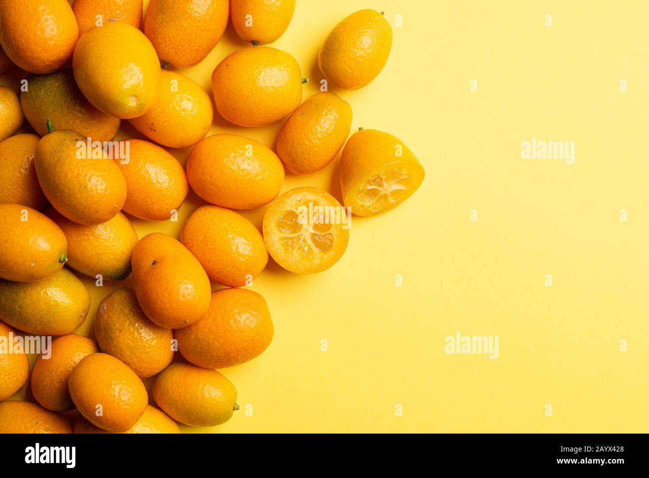 Pile of kumquat fruits, chinese tangerines, on yellow background. Stock Photo