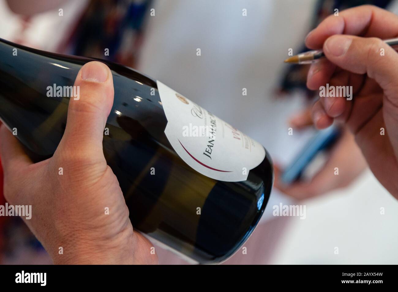 France Chablis 2019-06-21 Close-up hand of winemaker's leave signature on white label of Chablis Jean-Marc Brocard new vintage wine bottle Stock Photo