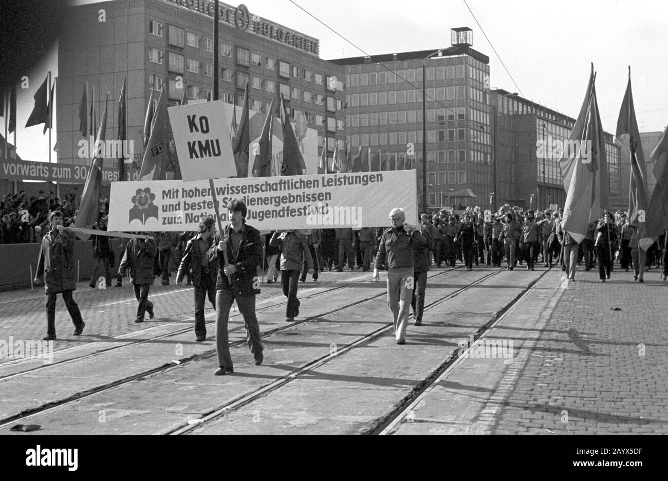 01 May 1979, Brandenburg, Leipzig: The demonstration on May 1, 1979 in Leipzig on the Ring, in the GDR called 'International Day of Struggle and Holiday of Labourers for Peace and Socialism'. Opposite the opera house was the grandstand 'Vorwärst zum 30. Jahrestag der DDR'), past which demonstration participants passed, here students of Leipzig's Karl-Marx-University (KMU) with a banner 'With high scientific achievements and best study results for the National Youth Festival'. In the background, residential buildings on the Ring with the advertisement for 'Balkancar - Bulgaria'. Photo: Volkmar Stock Photo