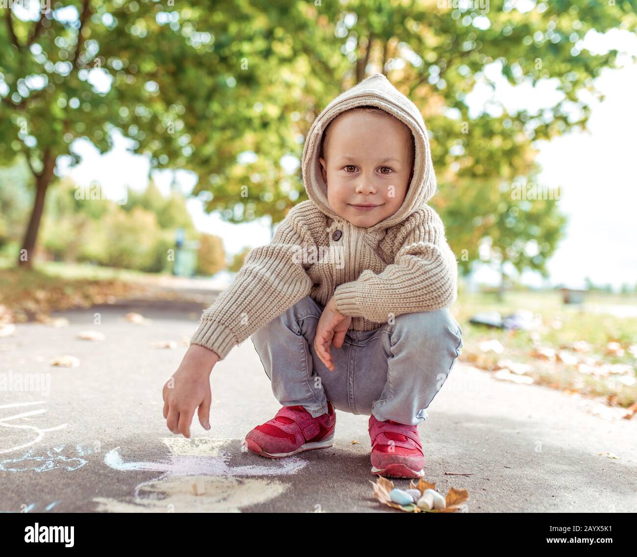 little boy summer city draws with crayons casual warm clothes beige sweater with hood. Creative creativity and art concept. Background autumn Stock Photo Alamy