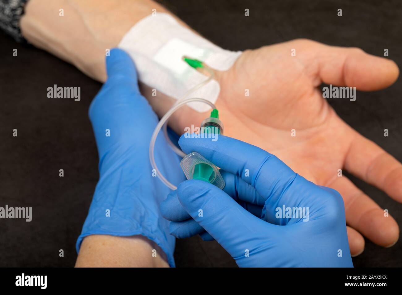 Doctor with blue gloves injecting medicine in a  vein catheter Stock Photo
