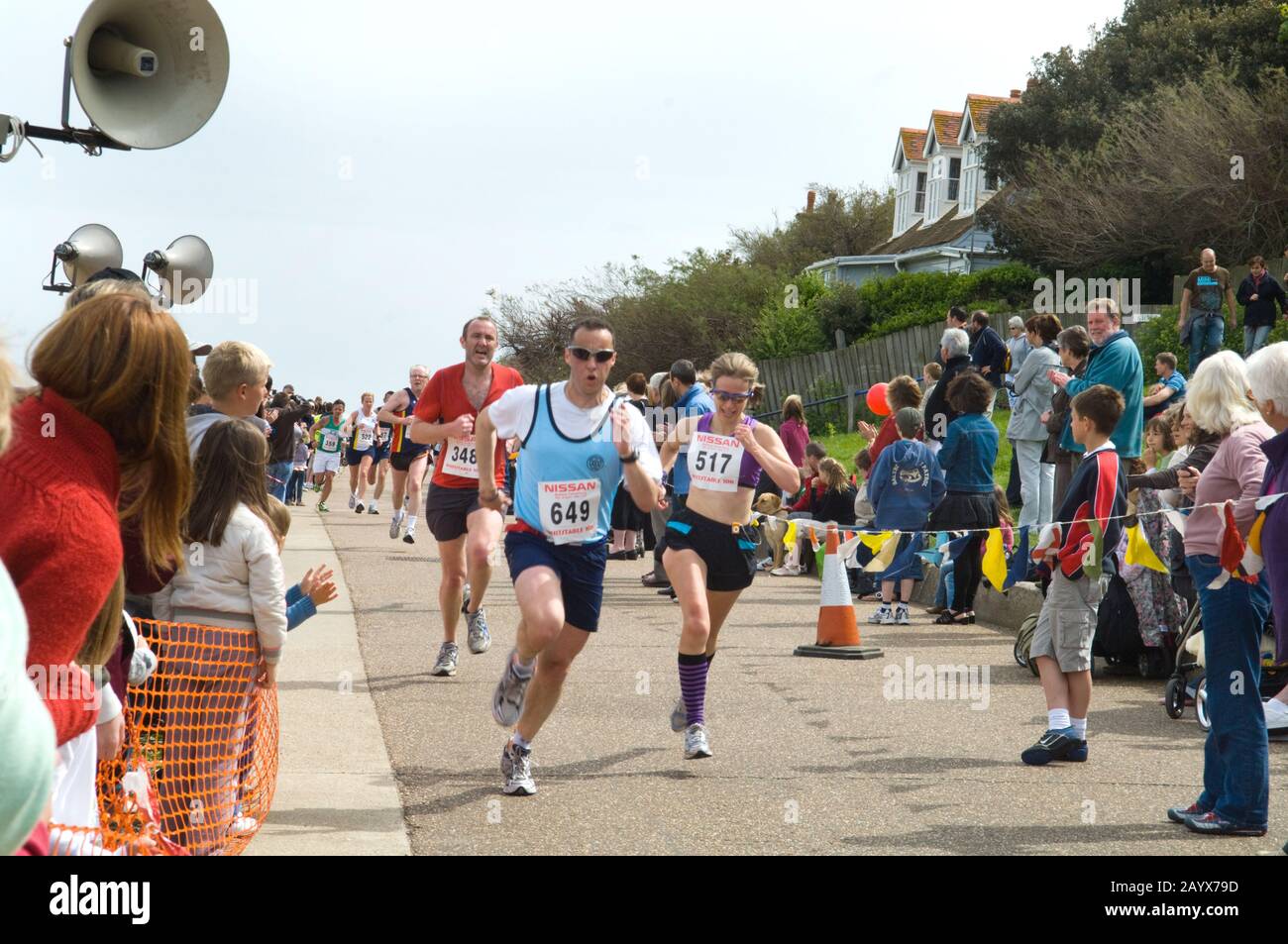 Runners and spectators at a 10KM charity run. Male an female runners in the centre race to the finish line. Stock Photo