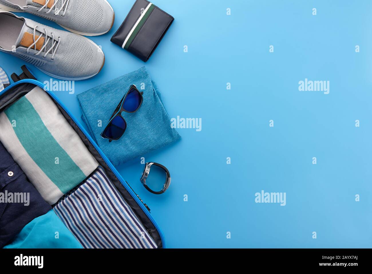 Travel suitcase with clothes on blue background Stock Photo