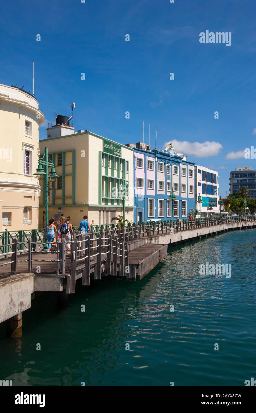Tourists walking along the old warehouses at the careenage harbor in