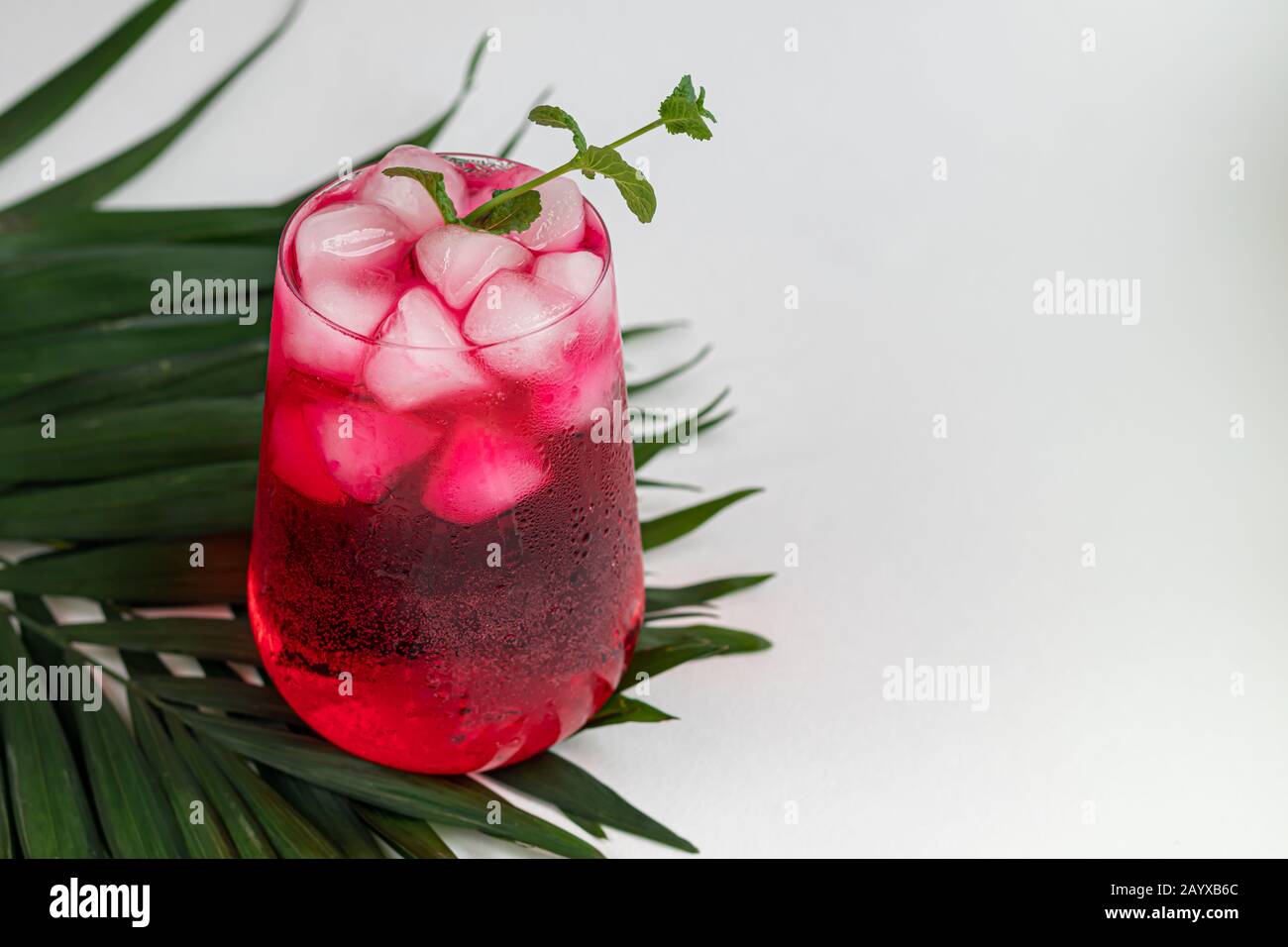 Raspberry-barberry drink in a transparent glass with ice. Added palm ...