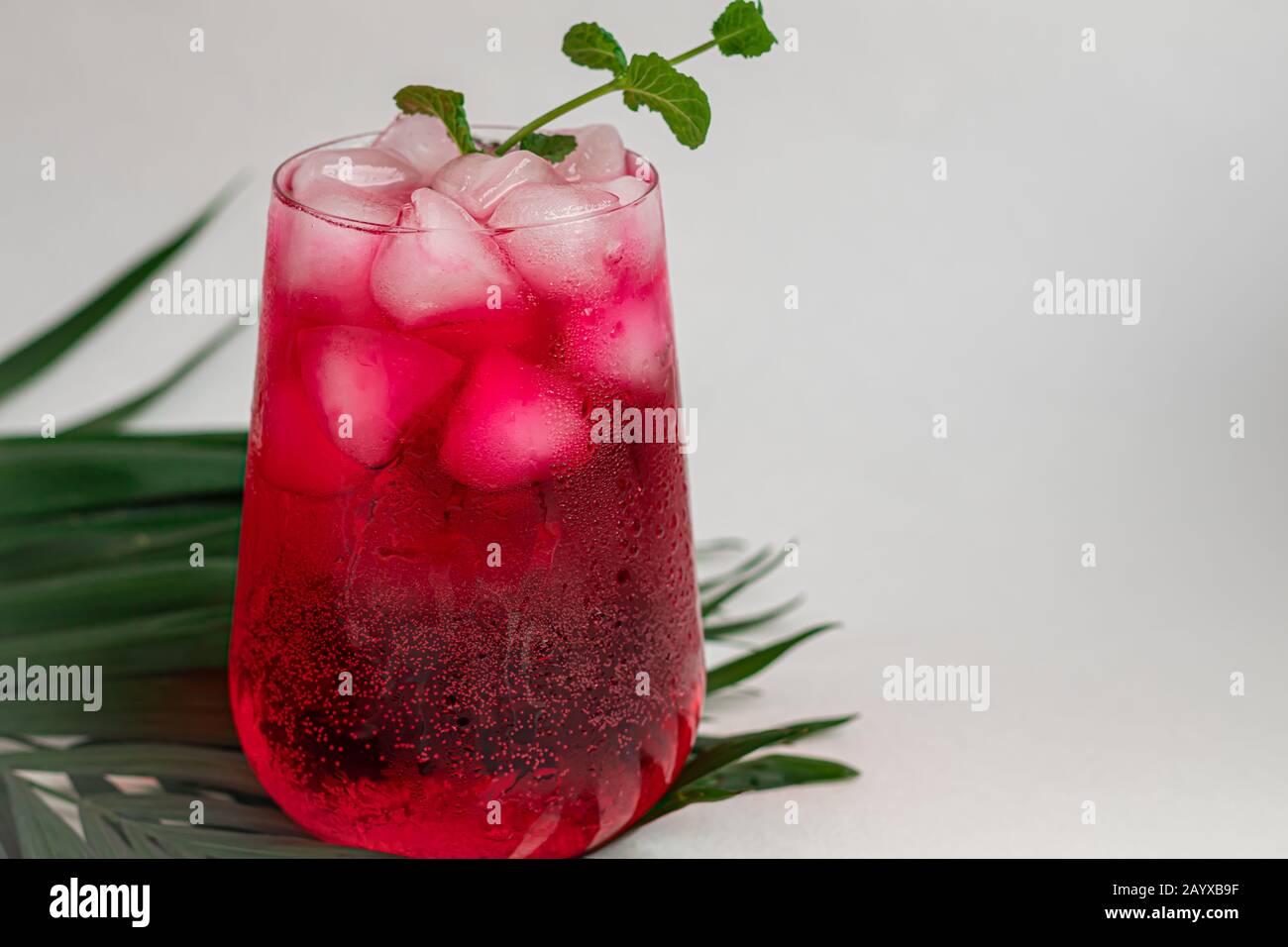 Raspberry-barberry drink in a transparent glass with ice. Added palm ...