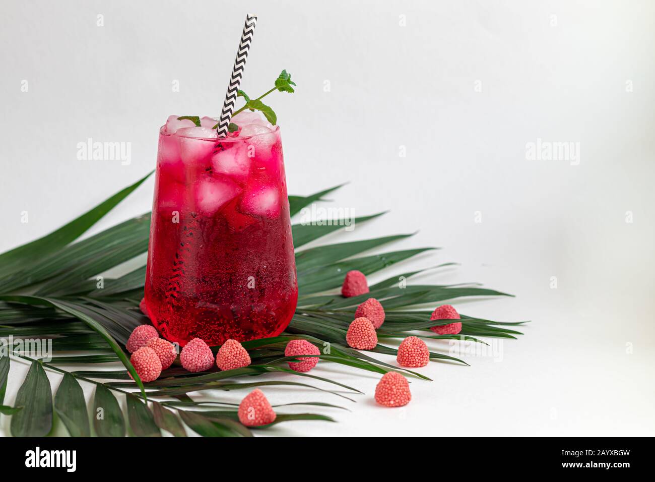 Raspberry-barberry drink in a transparent glass with ice. Added palm ...