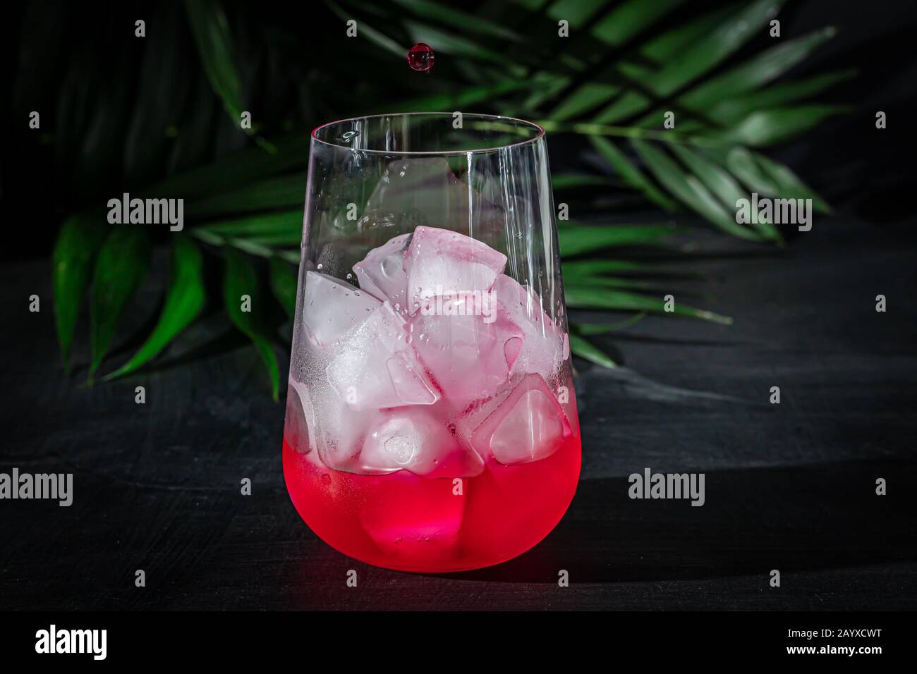 Raspberry-barberry drink in a transparent glass with ice. The drink is ...