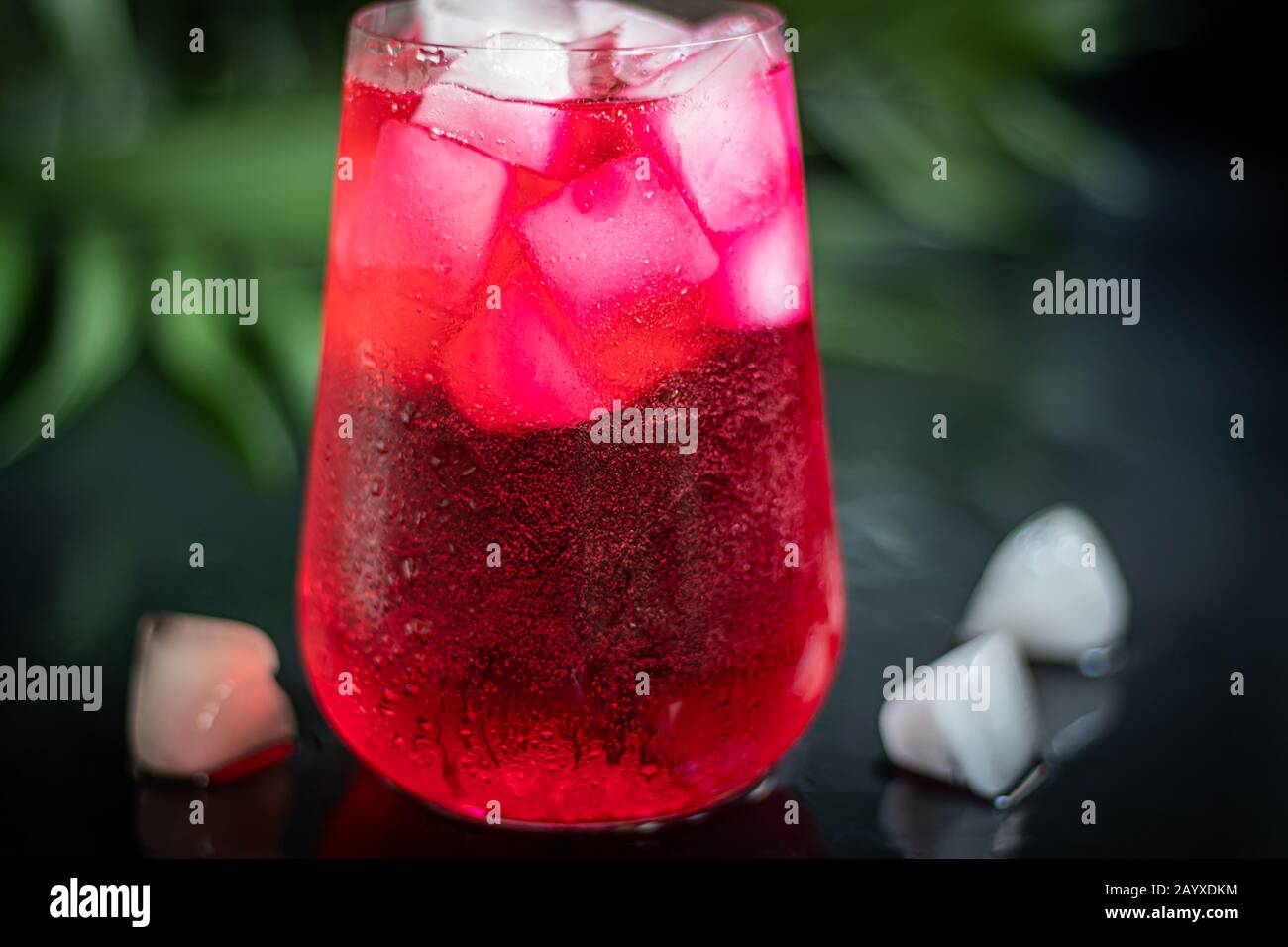 Raspberry-barberry drink in a transparent glass with ice. The drink is ...