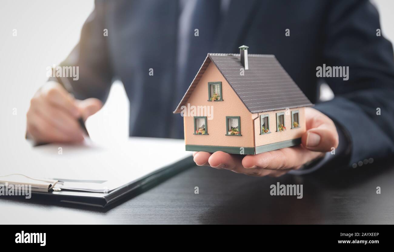 Real estate agent is holding a house model. Buy, loan for a house Stock ...