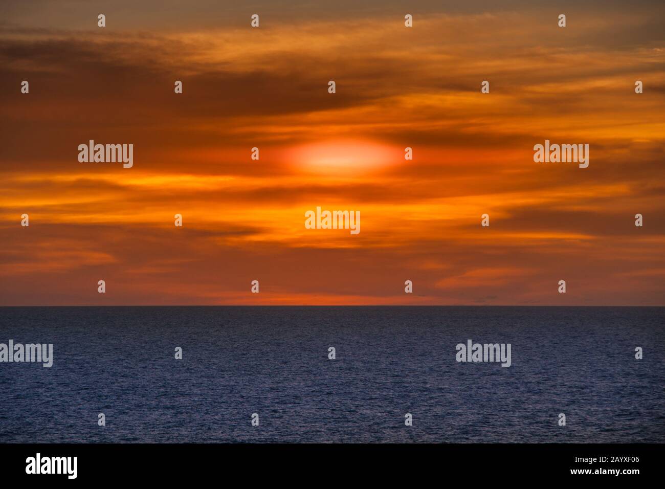 Timor Sea, Australai - December 1, 2009: Red sunset with brown cloudscape over dark blue sea. Stock Photo