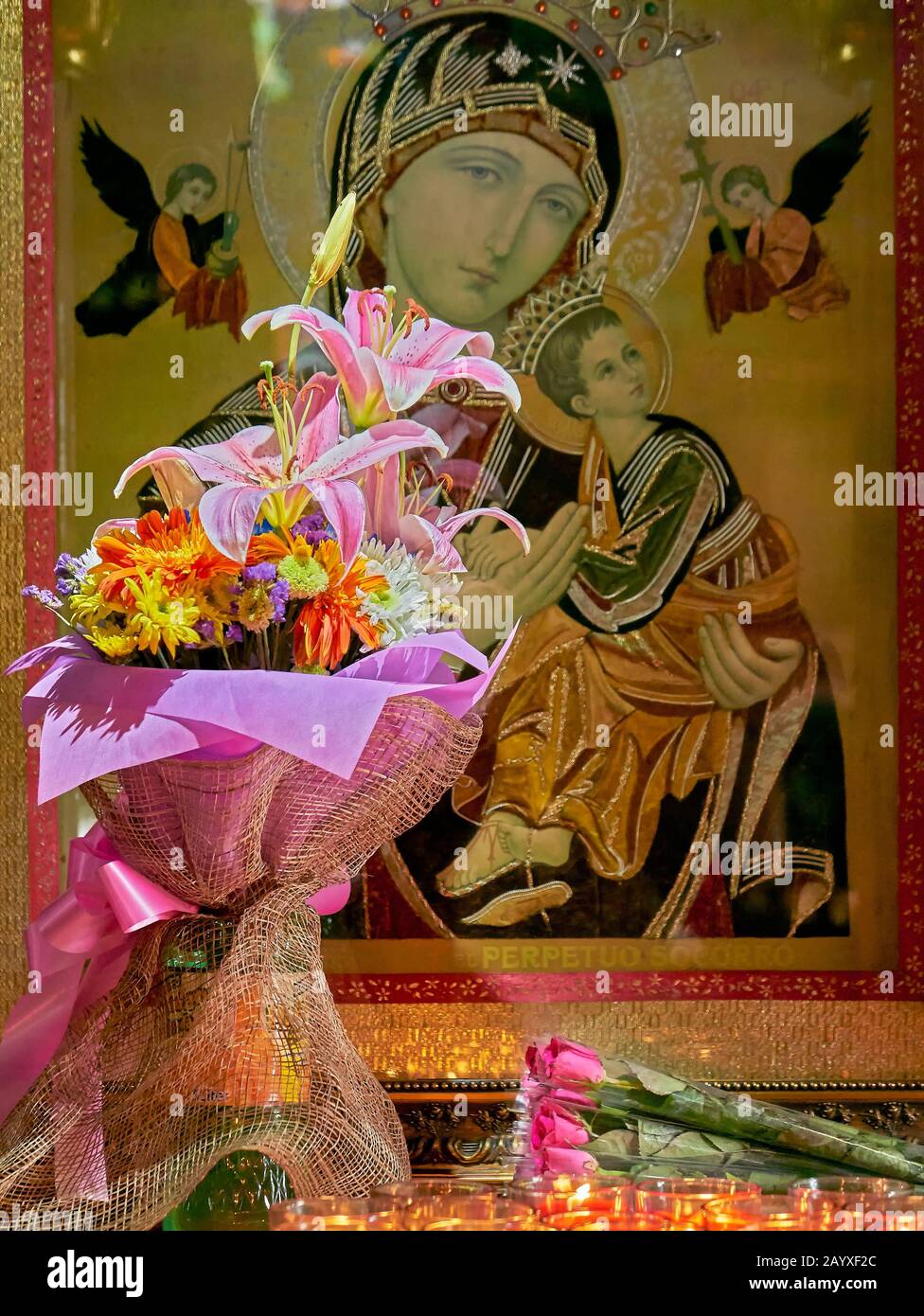 A bouquet of flowers, roses and candles in front of a picture of Mother Mary with Jesus, located at the Binondo church in Manila, Philippines Stock Photo