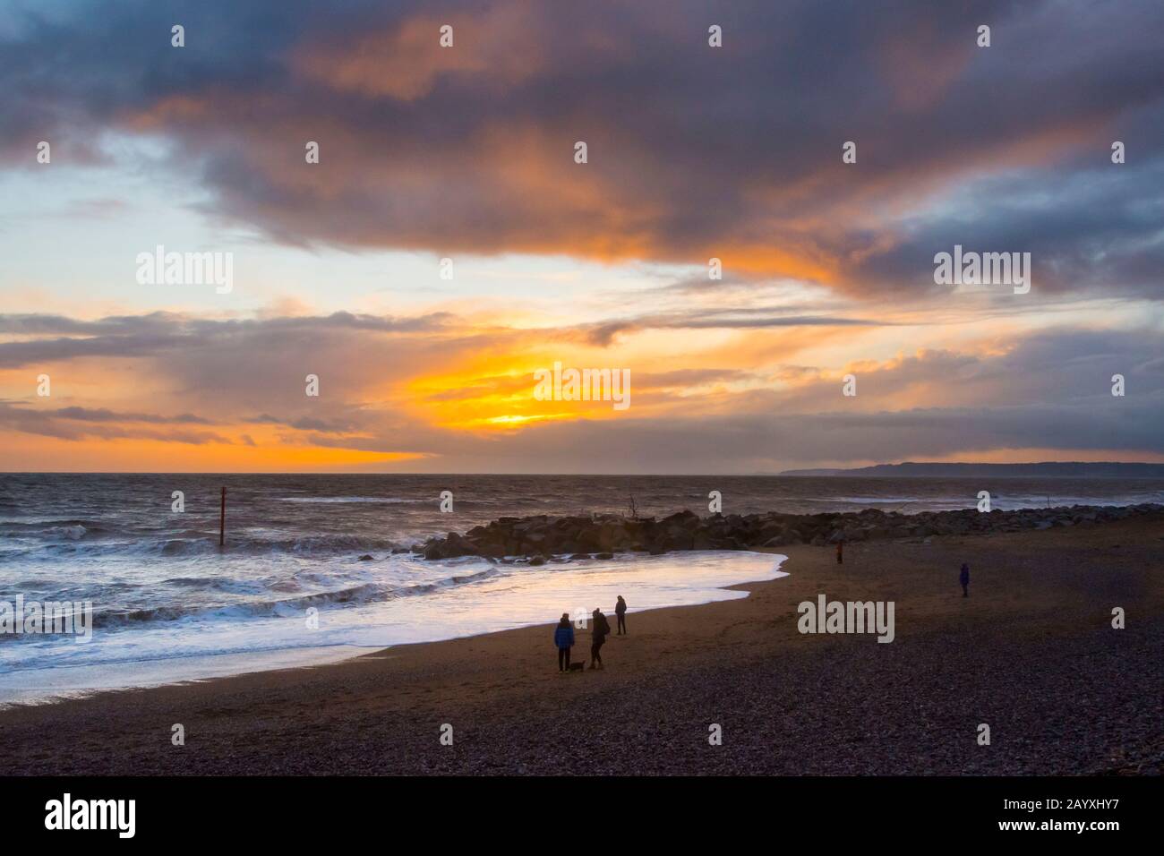 West Bay, Dorset, UK.  17th February 2020.  UK Weather.   People on the beach enjoying the moody sunset at West Bay in Dorset.  Picture Credit: Graham Hunt/Alamy Live News Stock Photo