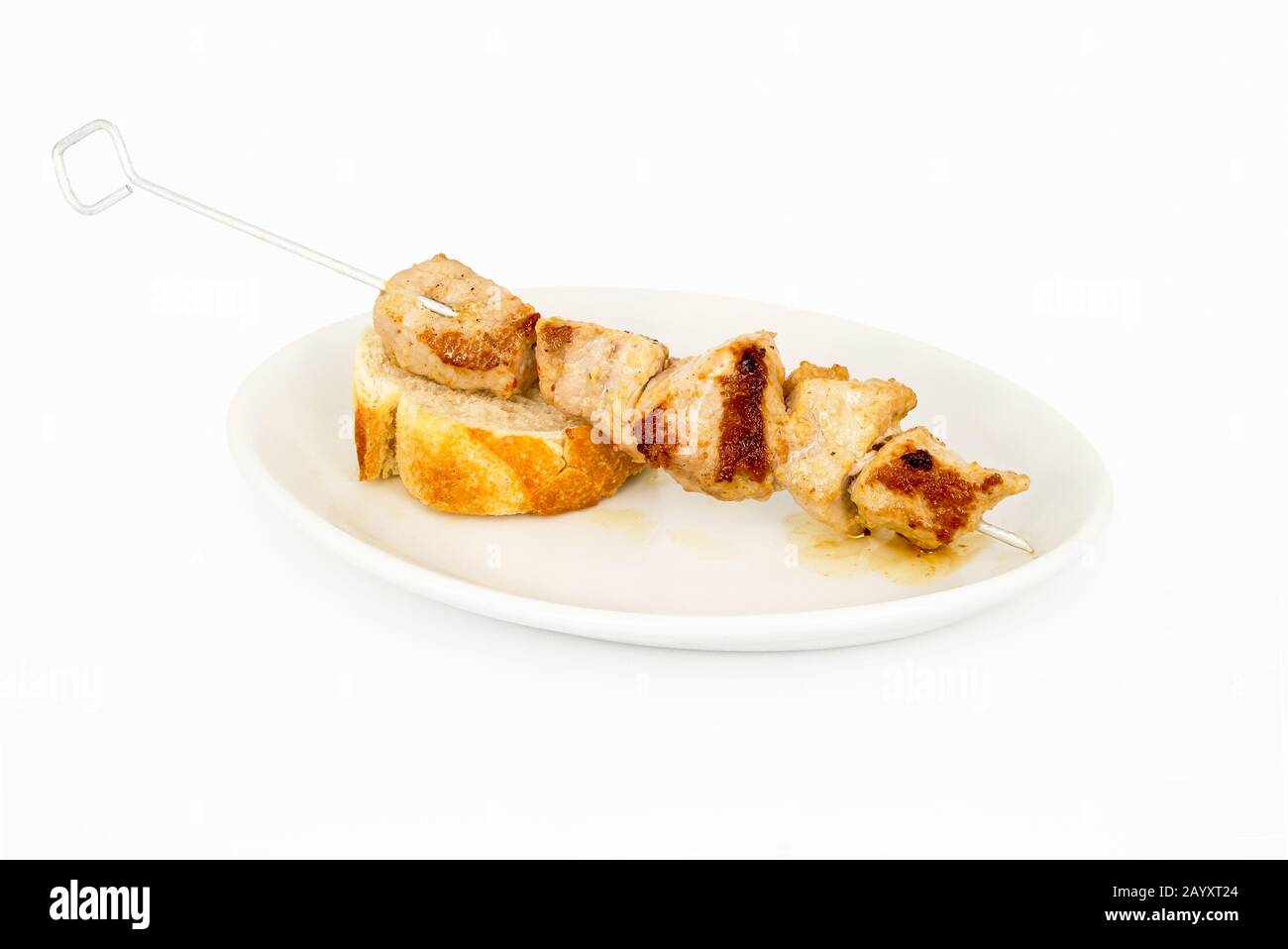 Skewer of meat on a slice of bread and on top of a white plate. Stock Photo