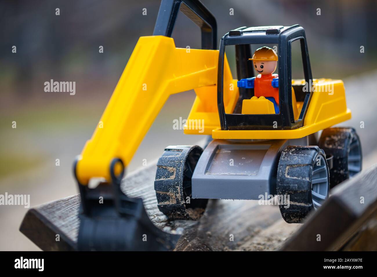 yellow digger with shovel for children standing in the sand of a playground for kids. Stock Photo