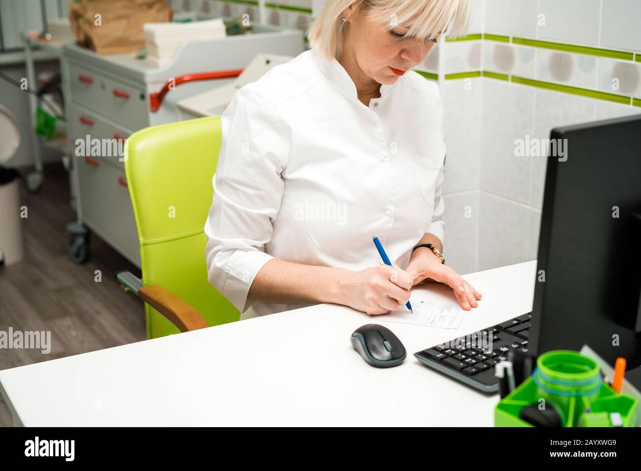 Female doctor sitting at a desk in a white medical coat  Stock Photo
