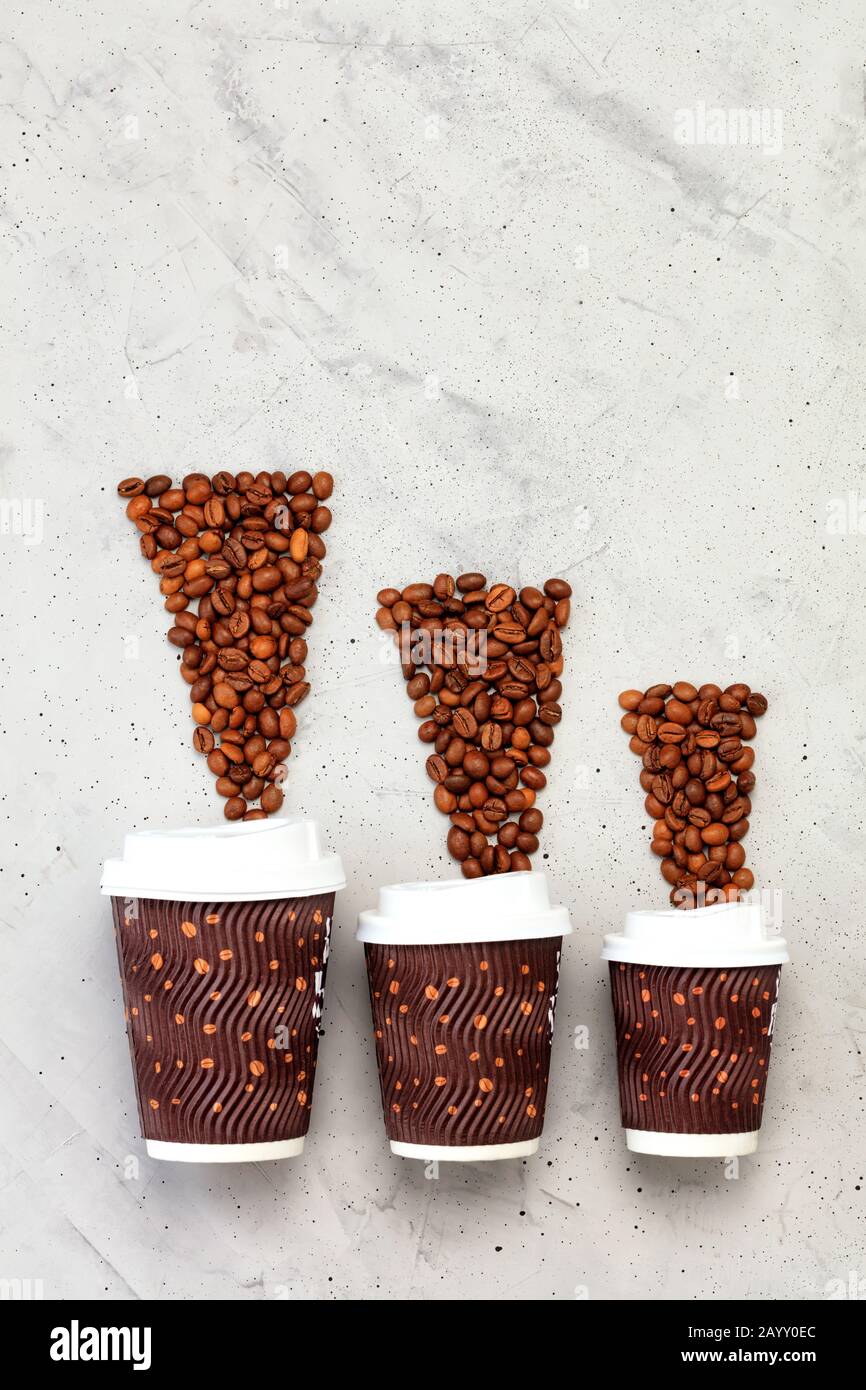 Coffee beans opposite three paper cups of different coffee capacities, vertical image. Stock Photo