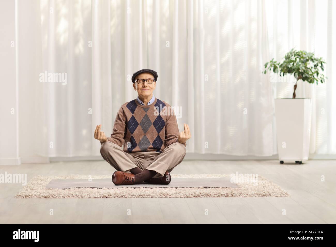 Elderly man practicing meditation at home Stock Photo