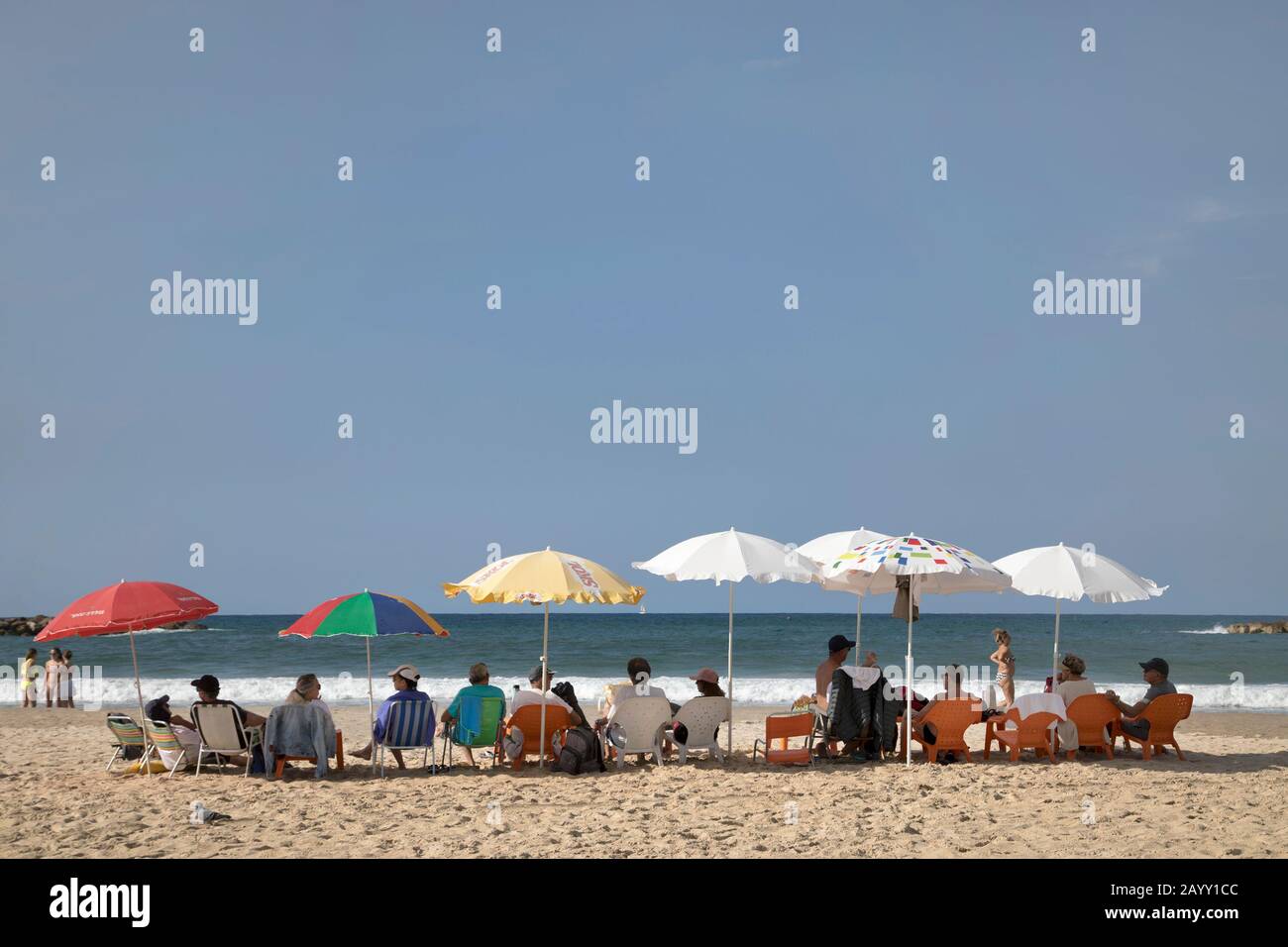 People relaxing under beach umbrellas looking out at the water on Gordon Beach, Mediterranean Sea coast in Tel Aviv, Israel Stock Photo