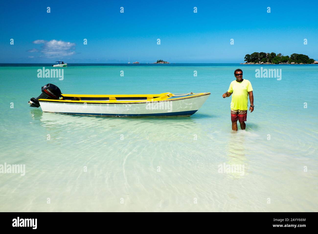 Taxiboat driver and his boat in clear waters off Praslin Island, Seychelles Stock Photo