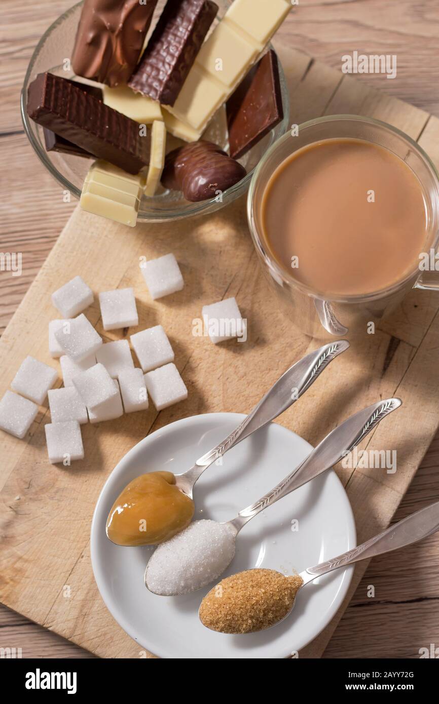 Different types of sugars and sweets lie on a wooden counter. Honey