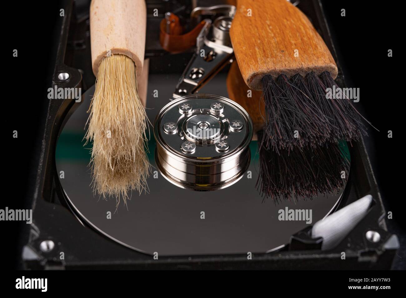 Cleaning the hard disk with a brush. Vacuuming old disk data on your computer. Dark background. Stock Photo