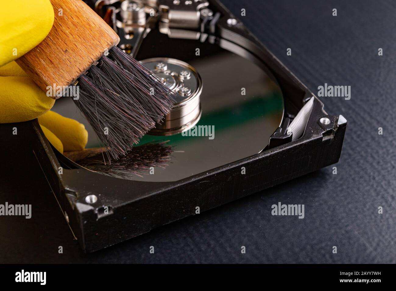Cleaning the hard disk with a brush. Vacuuming old disk data on your computer. Dark background. Stock Photo