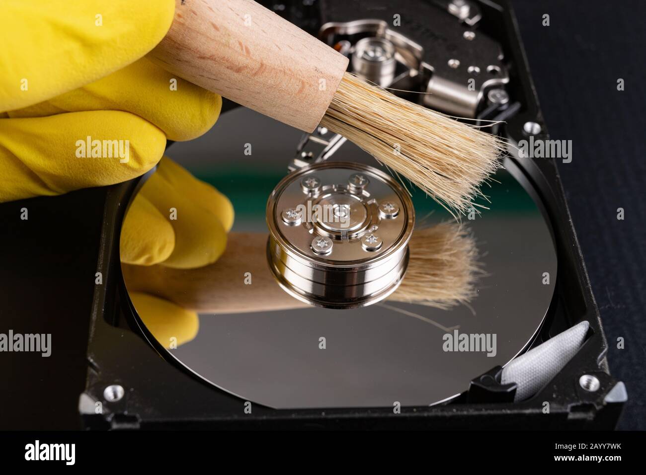 Cleaning the hard disk with a brush. Vacuuming old disk data on your computer. Dark background. Stock Photo