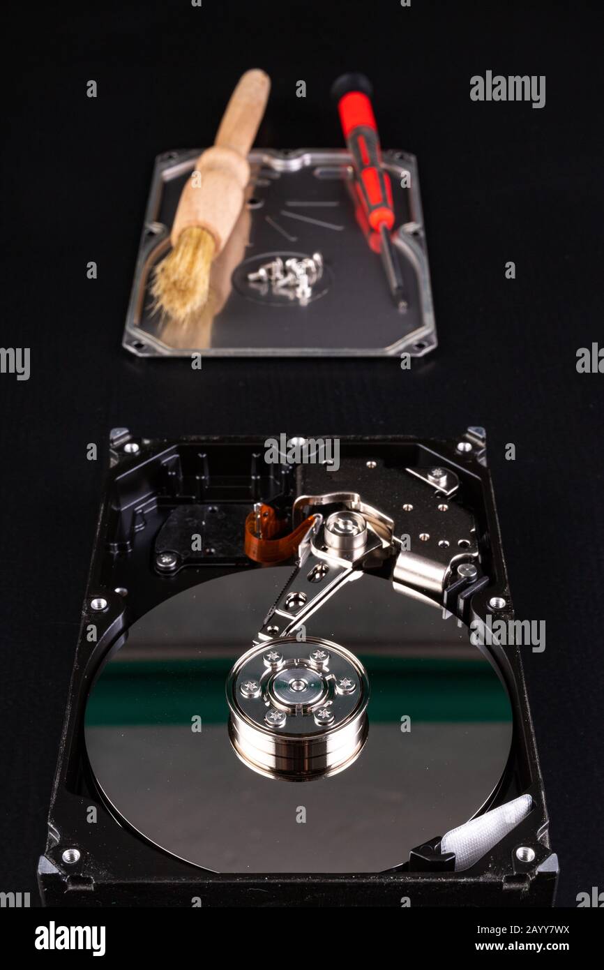 Cleaning the hard disk with a brush. Vacuuming old disk data on your computer. Dark background. Stock Photo