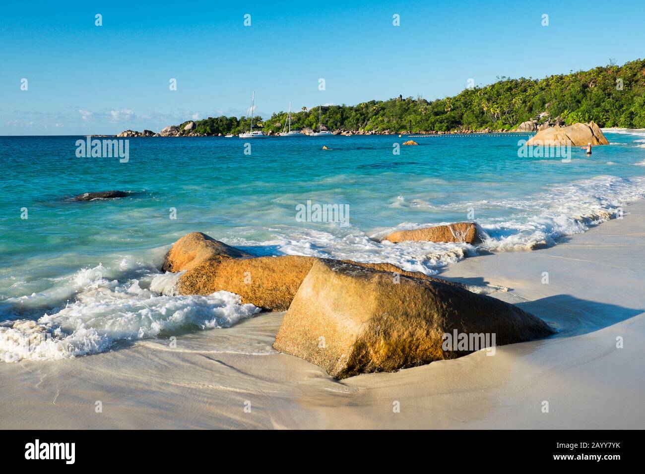 Waves rolling in on Anse Lazio beach and sailboats ancored near Pointe Chevalier on Praslin Island, Seychelles Stock Photo