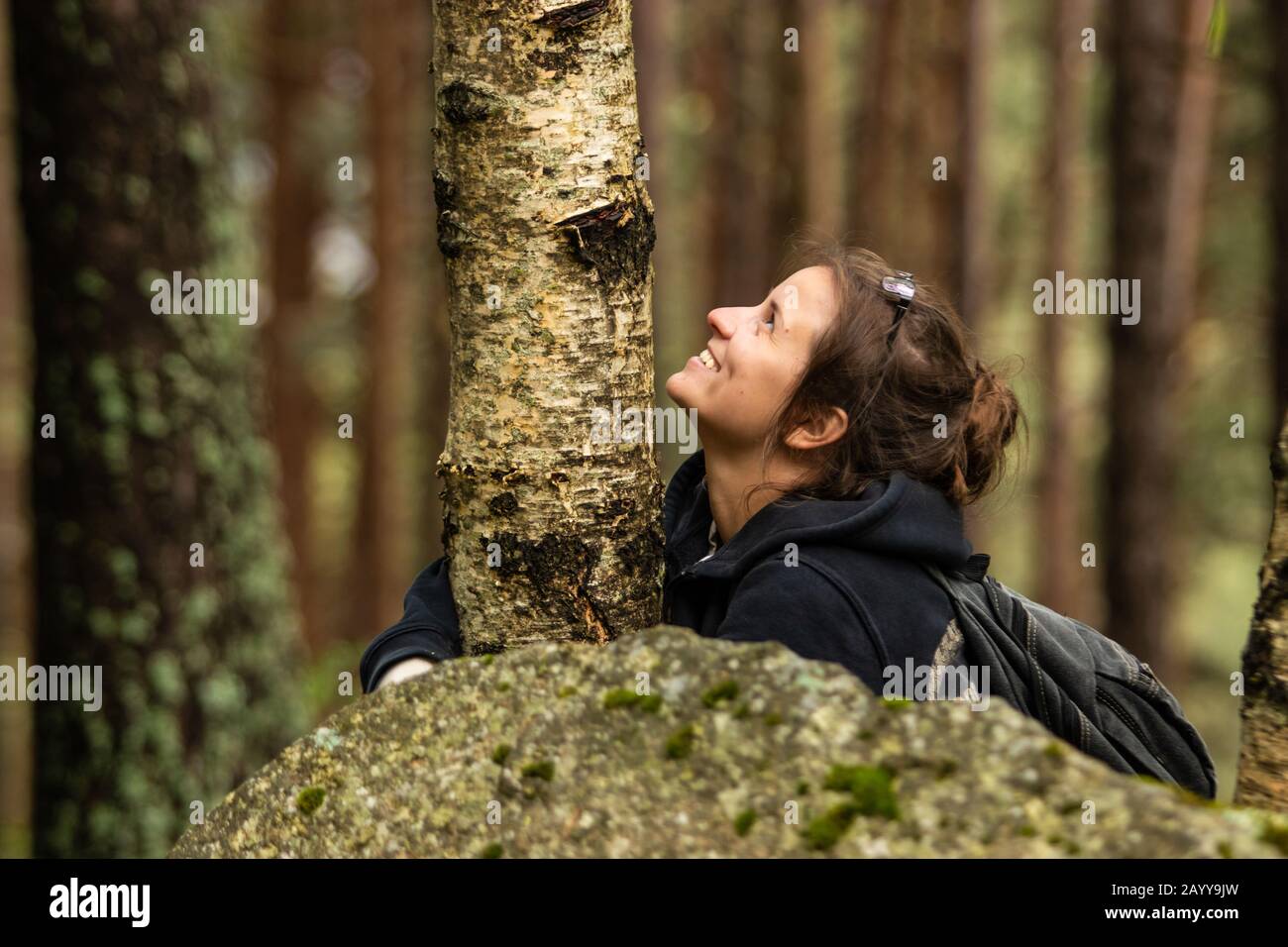 Tourist young woman hugging a tree and smiling in the forest during the ...