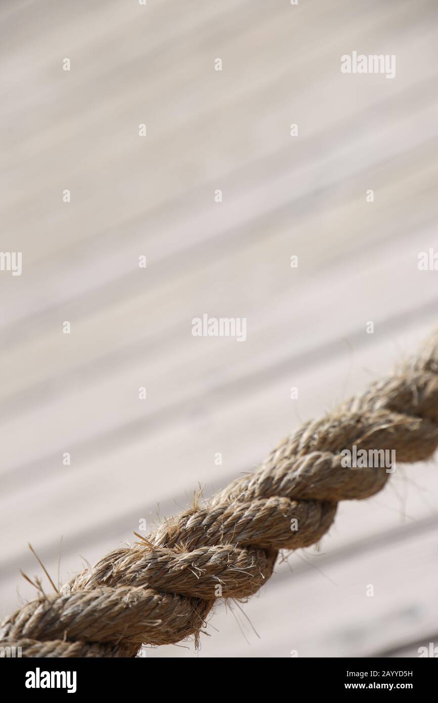 Aged rope with wooden floor boards in the background creating a natural aged texture for use as a background. Stock Photo