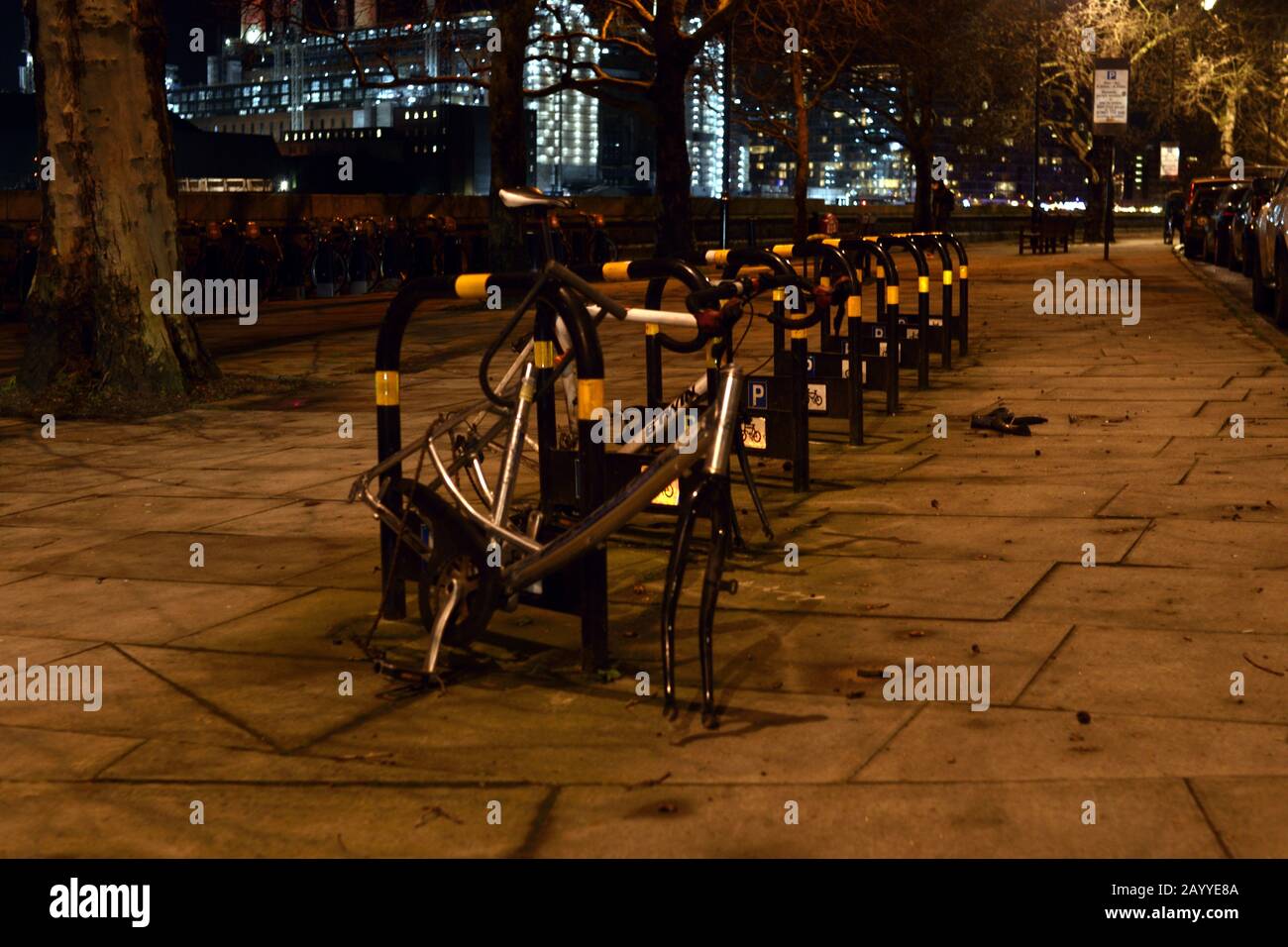 London, UK - 16 Deb 2020. Bike racks with abandoned broken bikes at night under sodium street lighting Stock Photo