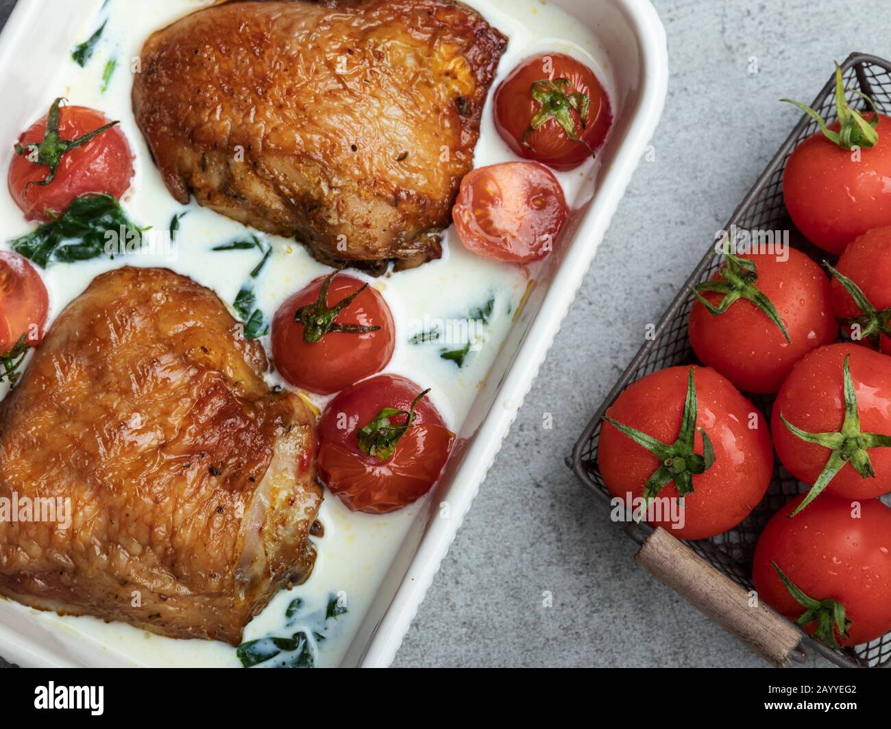 baked chicken thigh with creamy spinach and cherry tomatoes Stock Photo