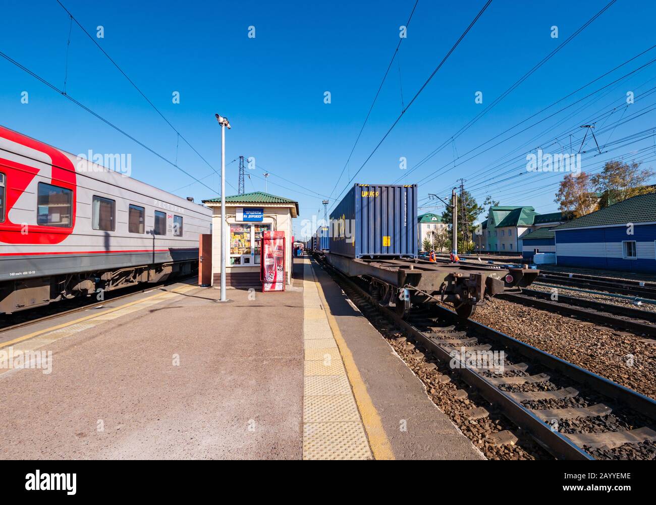 Freight train and Trans-Siberian Express at Marlinsk Railway station platform with food kiosk, Siberia, Russian Federation Stock Photo