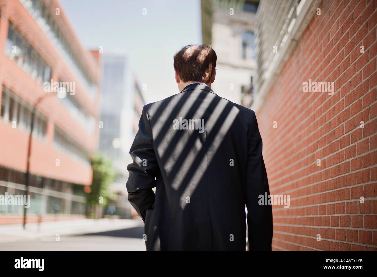 Rear view of a businessman in a suit walks outdoors. Stock Photo